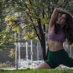 A young woman practices yoga in a lush park in Ciudad de México, surrounded by greenery.