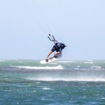 Dynamic kitesurfing action over ocean waves in Adicora, capturing the thrill of summer water sports.
