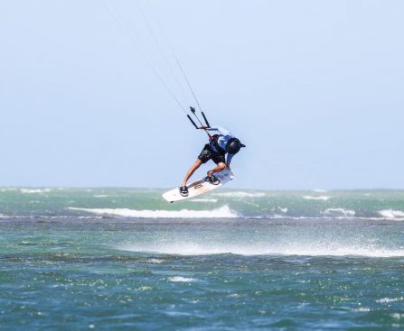 Dynamic kitesurfing action over ocean waves in Adicora, capturing the thrill of summer water sports.